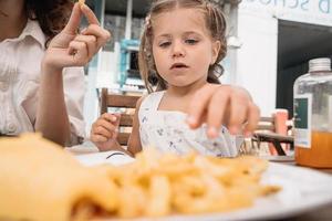 Mom and daughter eat french fries at an outdoor cafe photo