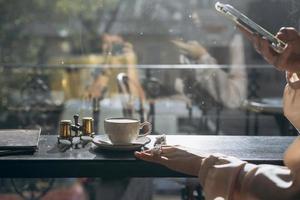 Attractive smiling girl taking photo cup of latte, using smartphone