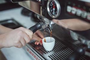Professional espresso machine pouring fresh coffee into white ceramic cup photo