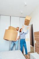 Happy couple holding cardboard boxes and moving to new place photo