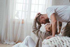 The guy on the bed kisses a girl who sits on the floor photo