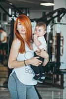 joven madre con su hijo pequeño en el gimnasio foto