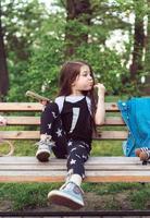 little girl with a smartphone sitting on a bench photo