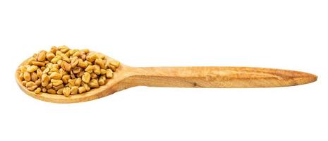 cuchara de madera con semillas de fenogreco aisladas foto