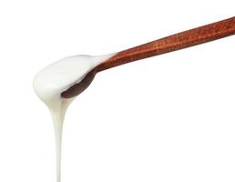 white honey pouring from little wooden spoon photo