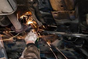 mechanic cleans silencer pipe by angle grinder photo