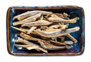 dried anchovy fishes in ceramic bowl isolated photo