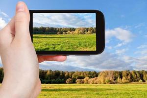 tourist taking photo of green meadow in autumn