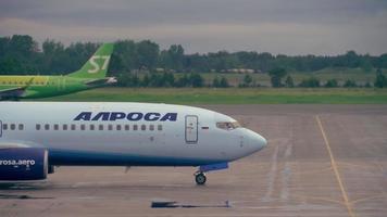 NOVOSIBIRSK, RUSSIAN FEDERATION JUNE 14, 2019 - Embraer E170 S7 VQ BYV accelerating on the runway for departure and Alrosa Aero Boeing 737 taxiing on the apron after landing, early morning. video