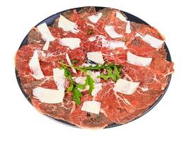 portion of Carpaccio dish on black plate isolated photo