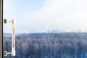 thermometer on window glass in cold winter day photo