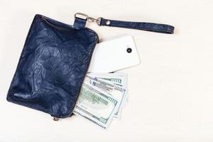 pouch bag with phone and US dollars on table photo