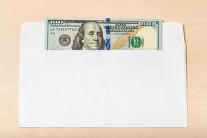one hundred dollars bill in open envelope on table photo