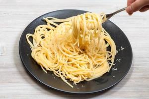 winding spaghetti on fork over black plate photo