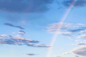 rainbow and gray clouds in blue evening sky photo