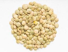 pile of raw light green lentils close up on gray photo