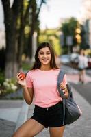 Young woman holding apple against a street background photo