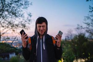 joven en el parque toma una foto en dos teléfonos inteligentes