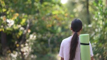 junge Frau wandert durch den Wald und trägt Yogamattenausrüstung video