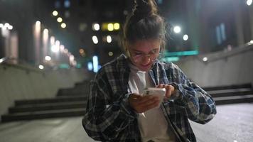 menina usando seu telefone na cidade à noite video