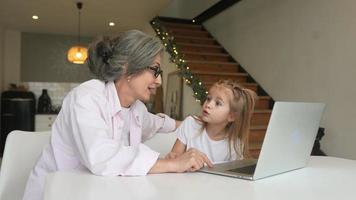 Little girl using computer at home with family video