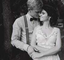 groom gently embracing his bride photo