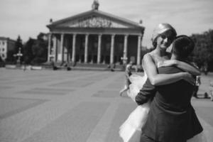 groom holds bride in his arms and twisted photo