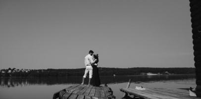 Hugging man and woman in love on wooden pier photo