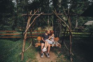 beautiful couple together with dog on a swing photo