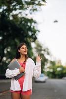 Young woman walking outdoors holding laptop computer photo