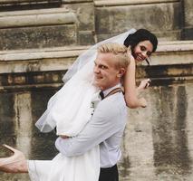 groom carries bride in his arms photo
