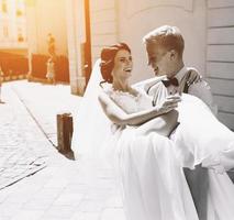 groom carries bride in his arms photo