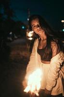 Young woman with torchlight on the beach at night photo