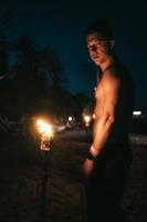 chico con antorchas en la playa por la noche foto
