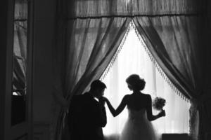 bride and groom standing in front of window photo