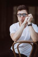 portrait of men sitting on chair with white t-shirt and sunglasses in the street photo