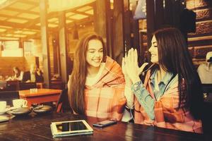 Two young and beautiful girls having fun in cafe photo