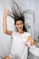 Young woman holds in hand to point shows to camera, care product bottle photo