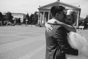 groom holds bride in his arms and twisted photo