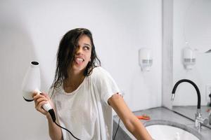 mujer hermosa joven en el baño sosteniendo un secador de pelo foto