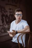 portrait of men sitting on chair with white t-shirt and sunglasses in the street photo