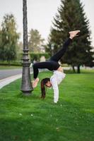 atractiva mujer flaca haciendo un backbend mientras muestra un salto mortal. foto