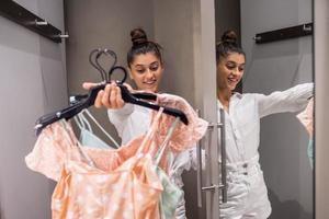 hermosa chica con mucha ropa en el fondo de la habitación en una boutique foto