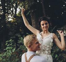 groom holds bride in his arms photo