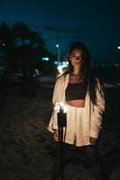 Young woman with torchlight on the beach at night photo