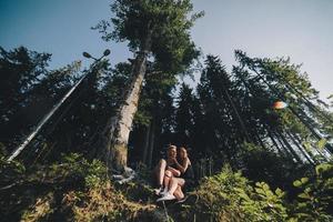 hermosa pareja sentada en un bosque cerca del árbol foto