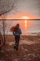 Woman enjoying time relaxing by the beautiful lake at sunrise. photo