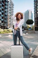 Stylish woman with suitcase looking at camera photo