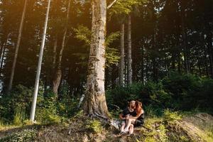 beautiful couple sitting in a forest near the tree photo