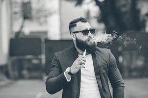 hombre con barba fuma cigarrillo electrónico foto